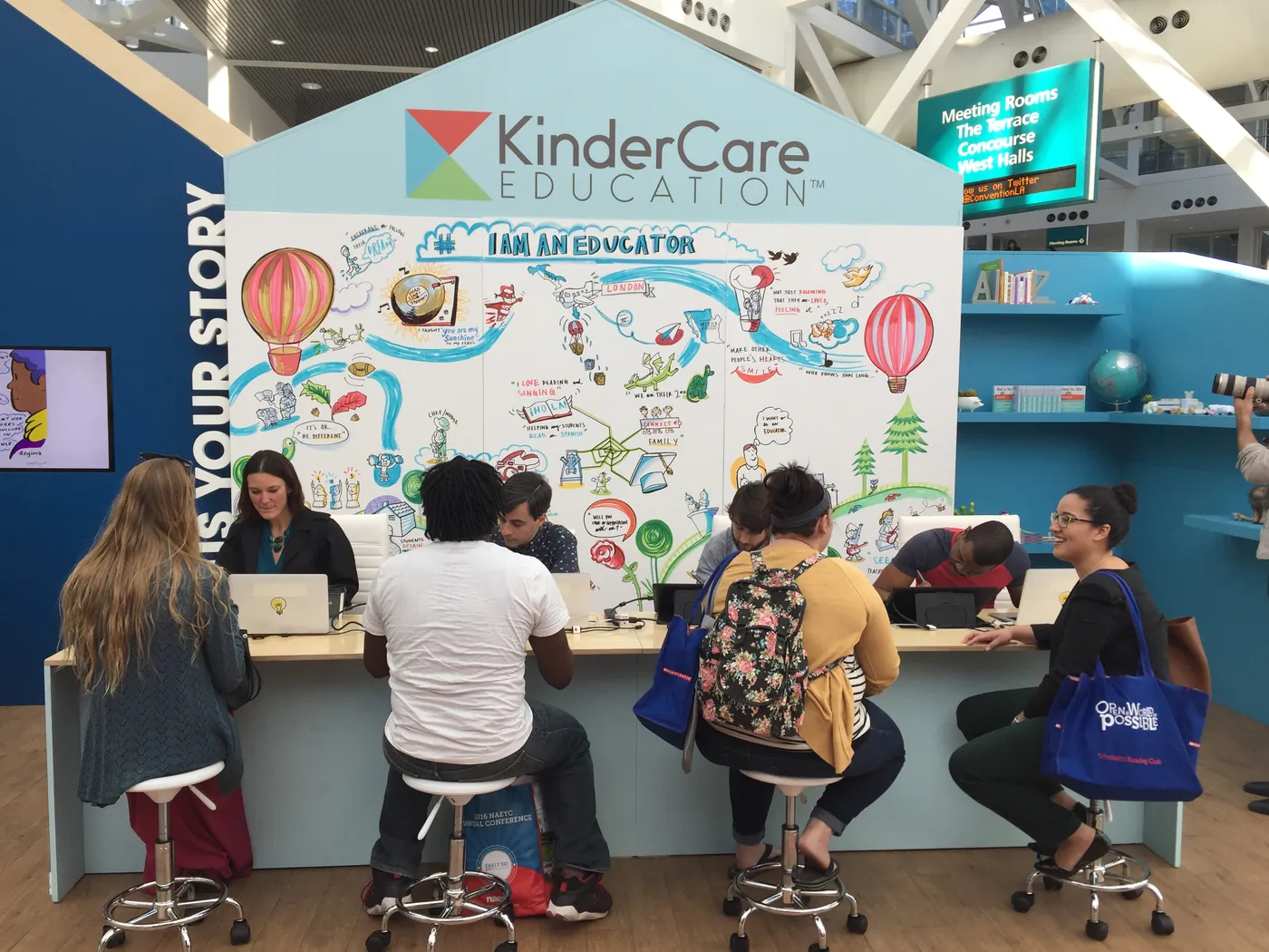 Visitors sit at a conference booth in front of a large ImageThink mural.