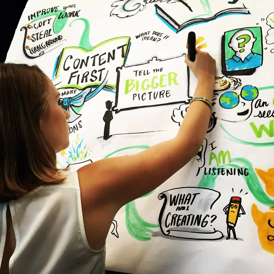 Graphic recorder drawing colorful visual notes on a whiteboard.
