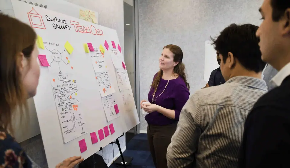 Facilitator leading a team through visual research clustering on a workshop wall.