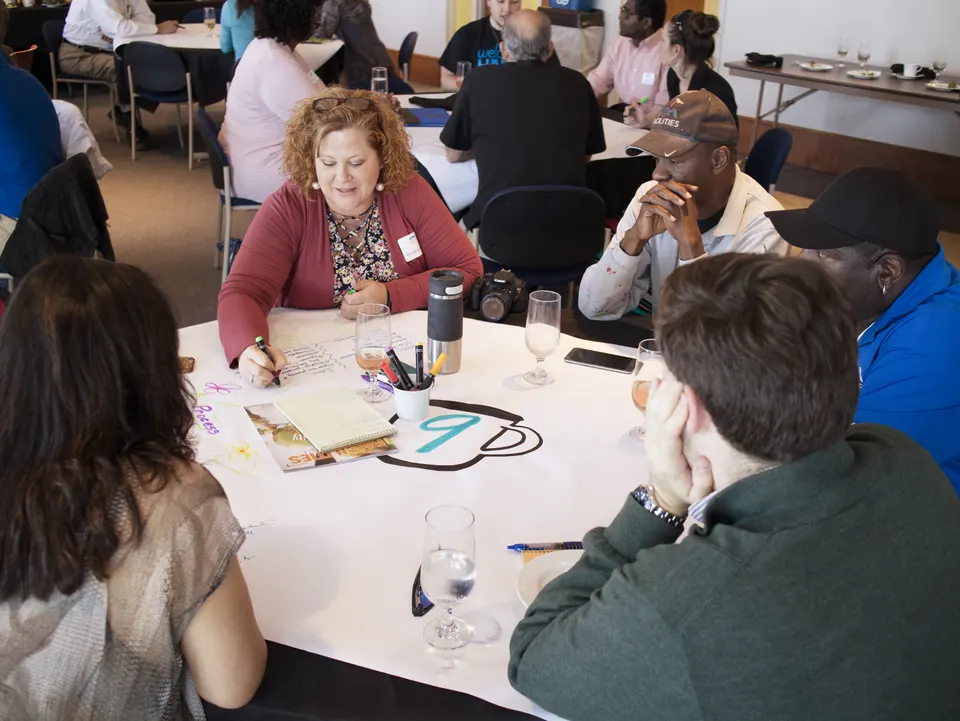 A team from University of Alabama Huntsville (UAH) collaborating at a circle table about sustainability.
