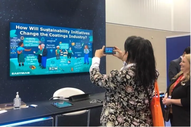 A conference attendee snaps a photo of ImageThink's work at the American Coating's Show for Eastman Chemical's booth