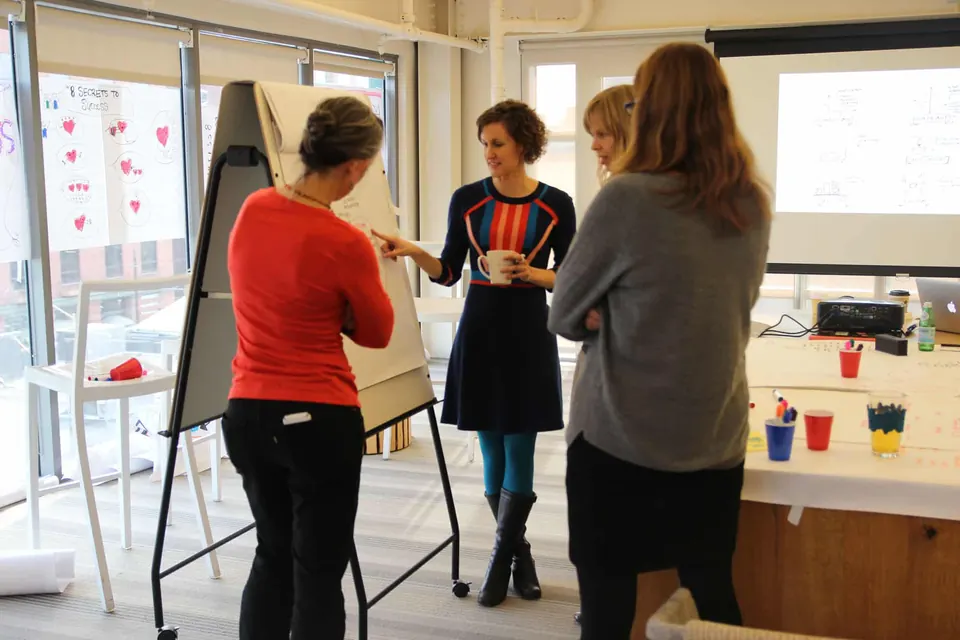 Nora Herting talking with a group and pointing to an easel