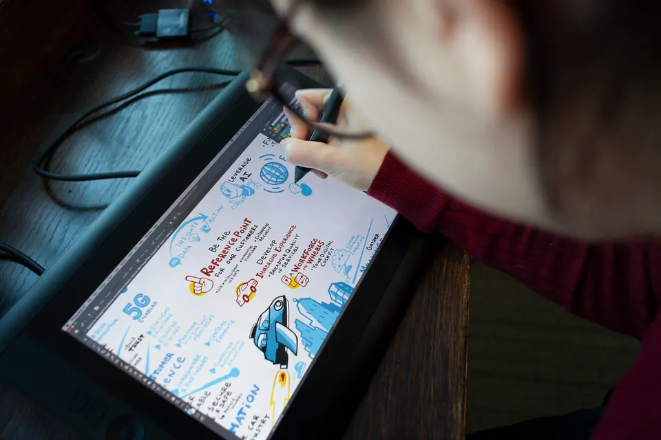 A graphic recorder drawing a remote meeting on a drawing tablet in the ImageThink studio